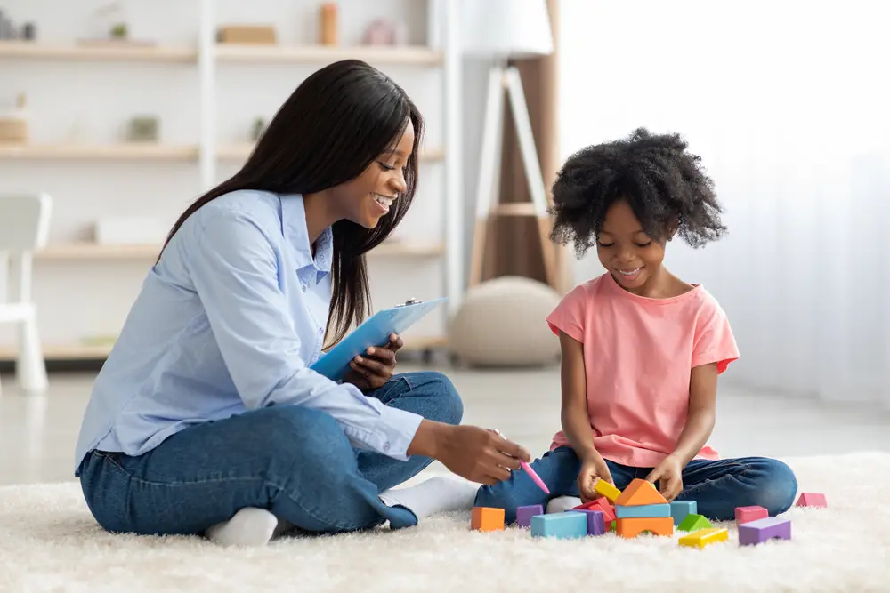 A counselor playing with building blocks with a young girl
