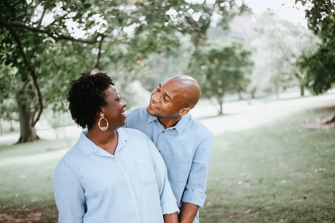 A husband and wife smiling at each other outdoors